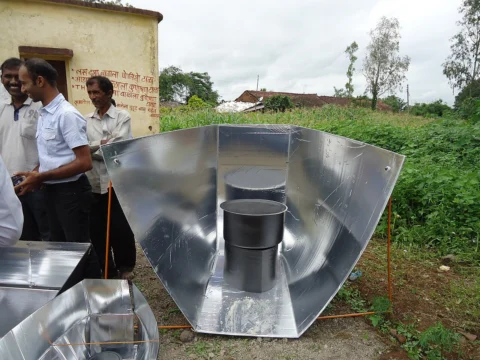 Solar cooker with reflective surfaces directing sunlight toward a cooking area.