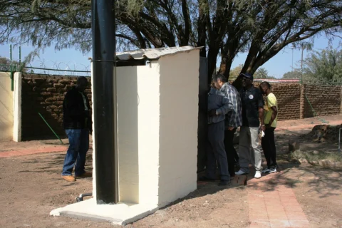 Otji toilet building with a ventilation pipe and people nearby