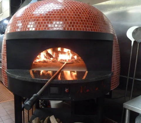 A large wood-fired pizza oven inside a restaurant.