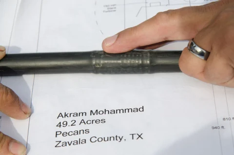Hands holding a drip-irrigation emitter over a farm plan