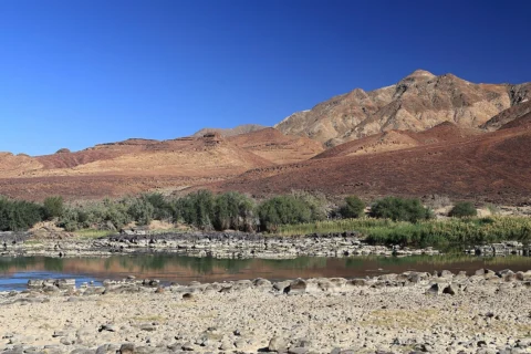 Orange River with a vegetated bank and arid mountains behind